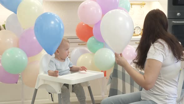 Mother and Baby are Preparing to Celebrate Children Birthday Blowing Up Balloons to Decorate Home