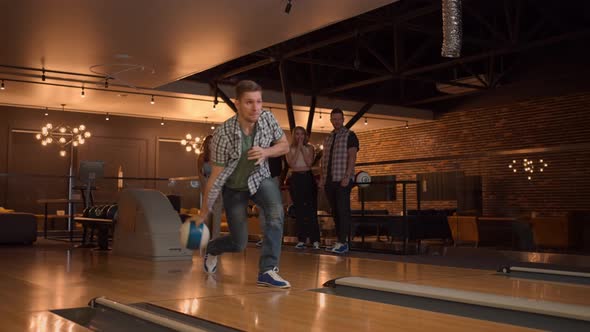 A Man Makes a Throw in a Bowling Club and Rejoices Emotionally Knocking Out Pins with a Ball alt