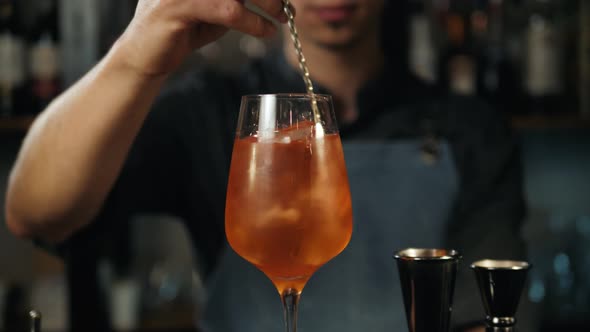The Barman Pours Aperol Into the Cocktail of Aperol Spritz Close Up Bartender Make Alcohol Drink alt