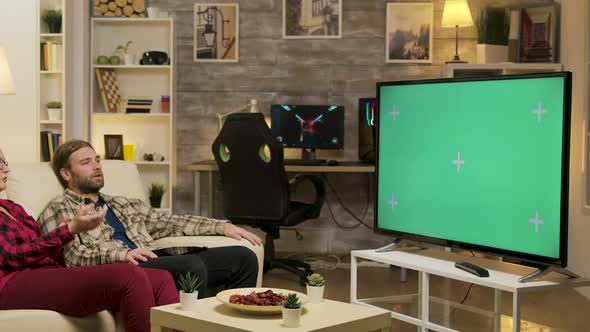 Couple Relaxing on Sofa Watching on Tv with Green Screen alt
