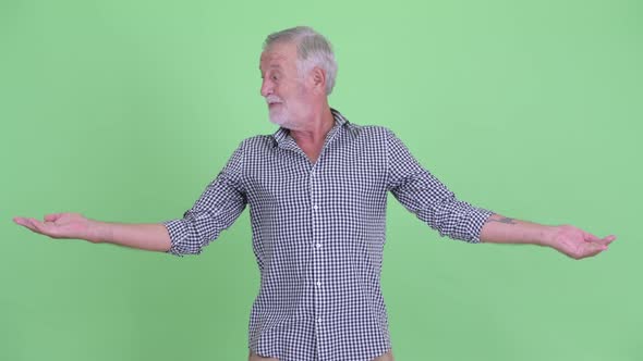 Happy Senior Bearded Man Comparing Something alt