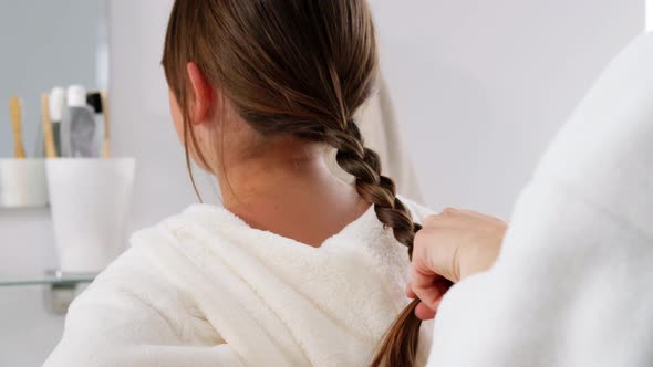 Mother and Daughter Braiding Hair in Bathroom