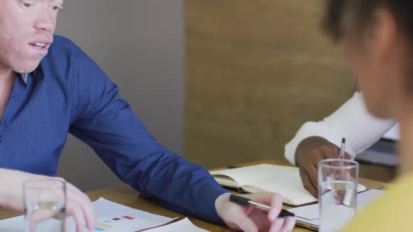 Diverse business people discussing with documents at meeting in creative office alt