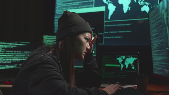 Young Asian Woman Hacker Using Computer Hacking And Upset, Code On Multiple Computer Screens alt