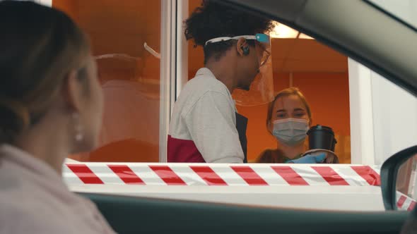 Close Up of Young Woman in Car Receiving Coffee in Drive Thru Fast Food Restaurant alt