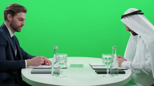 Arab Man in a White Kandura Sign Financial Documents with a Partner Businessman in a Suit While alt