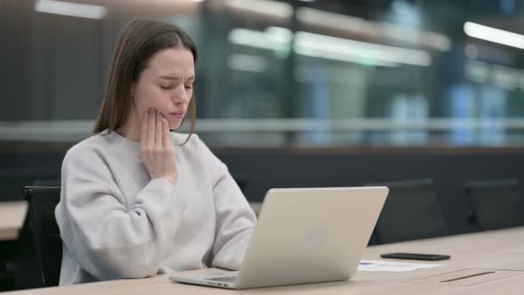 Woman having Toothache while Working on Laptop alt