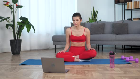 Fit Woman Sits on Yoga Mat Tells Fitness Trainer Study Online Video Call Laptop alt