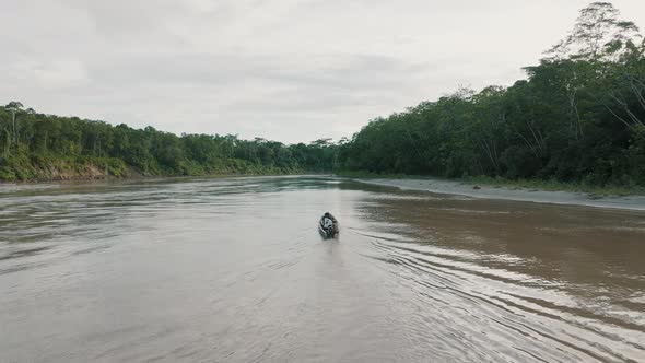 Aerial shot of backward view of boat sailing in the river at the Amazon forest. alt