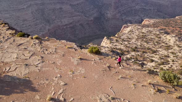 Aerial woman hiking on the edge of the San Rafael River Canyon in Utah alt