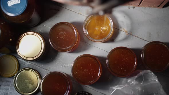 Top Down View of Pure Honey Glass Jars, Freshly Extracted Golden Liquid Bee Honey Flowing and Drippi alt