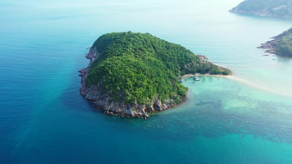 Thailand islands, aerial, Green cay with palms and rocky coast in the endless aquamarine ocean. Hear alt