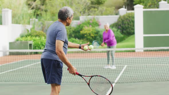 Video of biracial senior man holding racket and starting match on tennis court alt