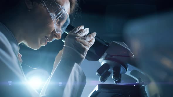 A Woman Scientist is Looking Into Microscope Biochemical Research alt