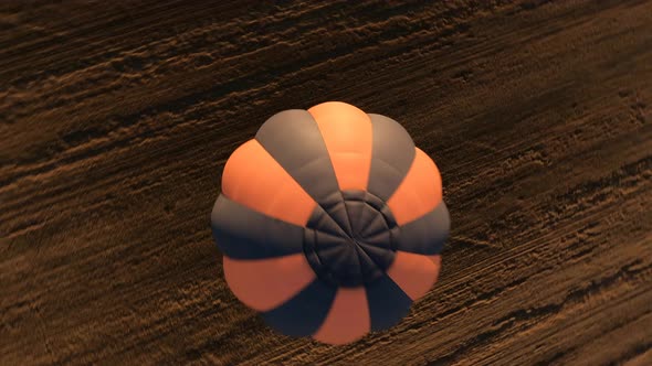 Orange Hot air ballon floating above sloping field at beautiful sunrise