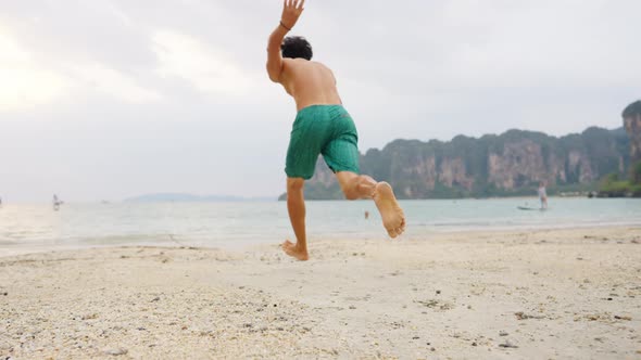 4K Young Asian man swimming in the sea at tropical lagoon island beach in summer sunset. alt