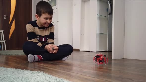 Boy playing with spider robot toy on the floor at home alt