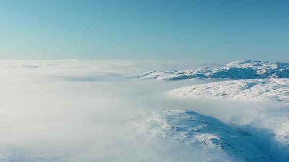 Flying over clouds and snow-capped peaks. Aerial view of the snow-capped mountain peaks.
