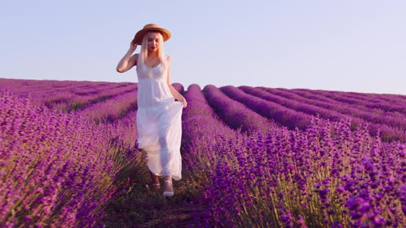 Young Woman in White Dress Walking Through a Lavender Field on Sunset