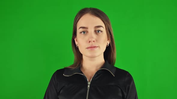 Happy Young Woman Poses for a Portrait on Green Screen. Looks at the Camera