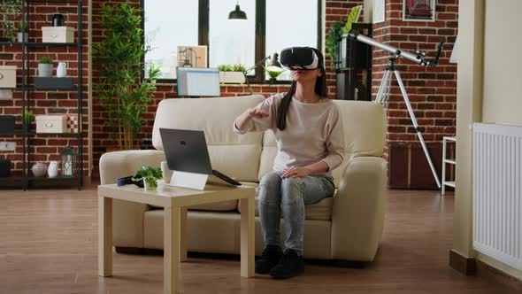 Playful Woman with VR Goggles Playing on Metaverse Inside Living Room alt