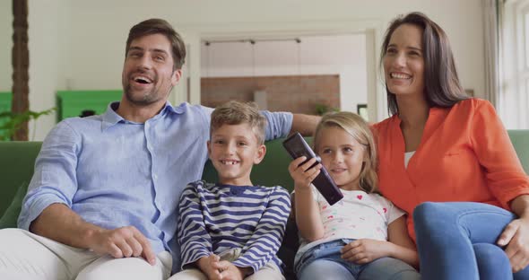 Family watching television together in living room at home 4k alt