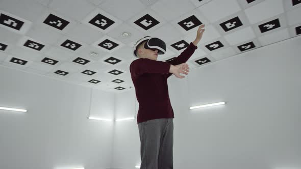 Little Boy in Brown Sweater Is Using His Hands in Virtual Realty Wearing a Headset in an Empty alt