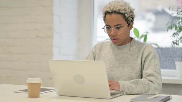 African Woman Coughing While Using Laptop in Office alt