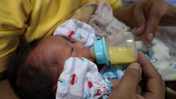 The newborn is eating breast milk from a bottle, slow-motion shot alt