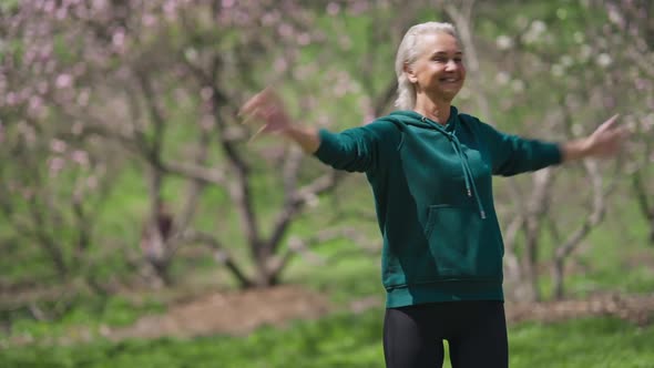 Fit Smiling Senior Sportswoman Exercising in Sunny Park on Summer Day alt