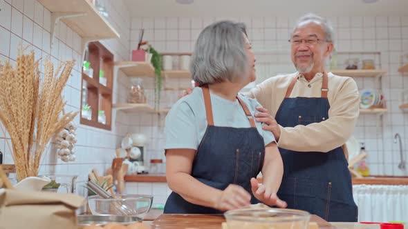 Asian Senior elderly couple standing in kitchen at house feeling happy and enjoy together. alt