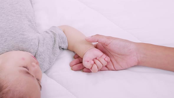 Close up of Mother holding hands her newborn baby. Happy kid, cute family. Mother love and fidelity.