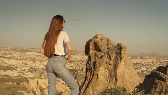 Confident Woman Traveler Admiring Rocky Cliffs in Morning in Cappadocia