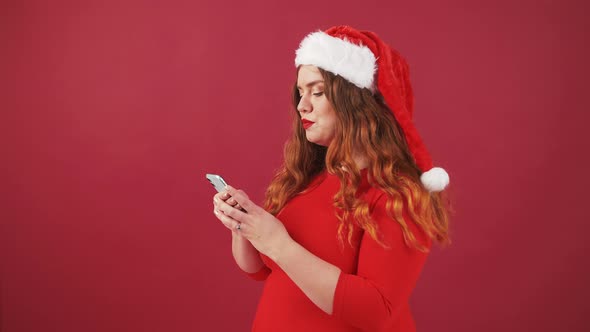 Shocked Oversize Woman in Santa Christmas Hat Using Mobile Phone Receiving Message and Enjoying alt