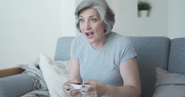 Very Passionate Elderly Person Relaxes on the Couch at Home and Plays Video Games alt