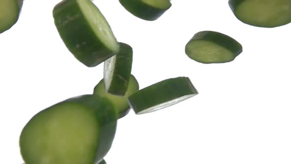Halves of Wet Green Cucumber Slices are Falling and Rotating on White Background alt