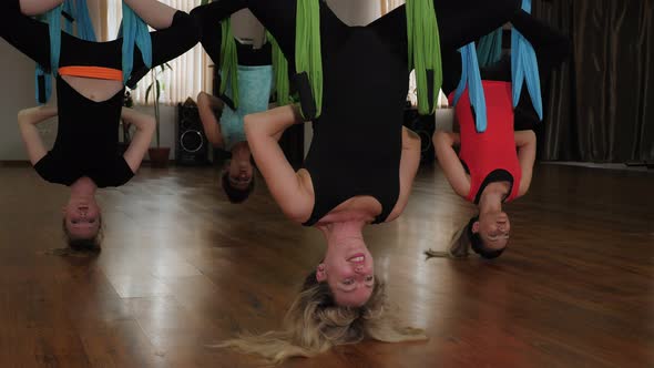 A Group of People Hang Upside Down in a Hammock alt