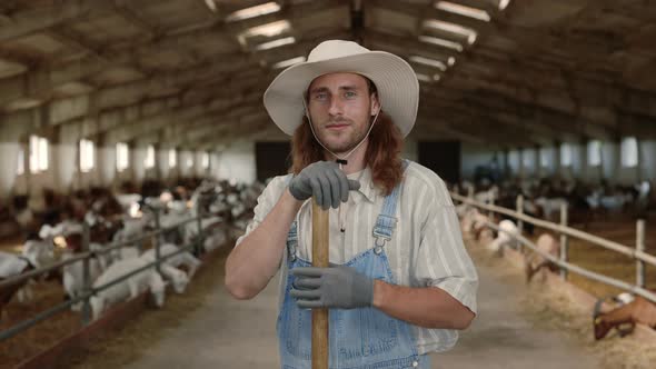 Positive Caucasian Farmer Holding Shovel at Ranch with Goats alt