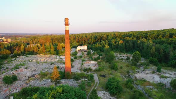 Old brick pipe among nature. Tall factory tower on abandoned place in the countryside alt