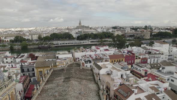 Drone flying over Santa Ana church roof with Guadalquivir river and Cathedral in background.
