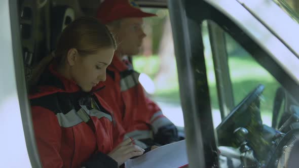 Doctor Writing Report in Ambulance, Smiling to Camera, Emergency Medicine Reform alt