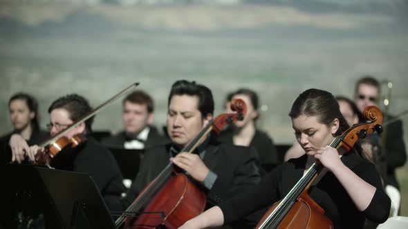 Shot of outdoor orchestra, close up on the musicians playing string instruments alt