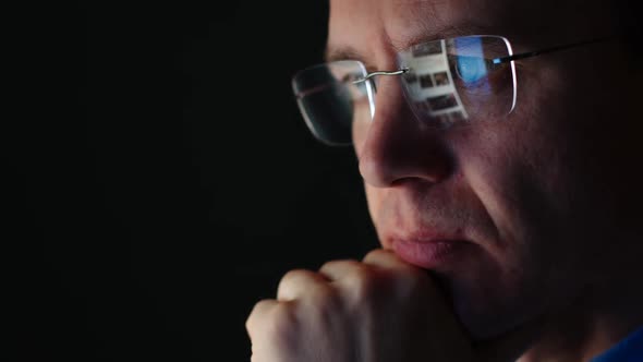 REFLECTION: Face of adult businessman in an eyeglasses looking a website