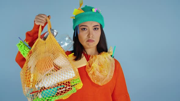 Woman holding package with plastic garbage and showing on it by finger.