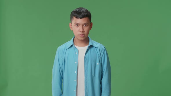 Terrible Asian Boy Looking At Camera In The Green Screen Studio alt