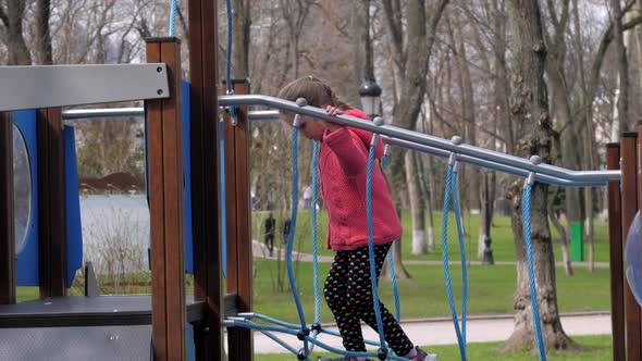Junior Schoolgirl Walks Along Suspension Bridge in Park alt