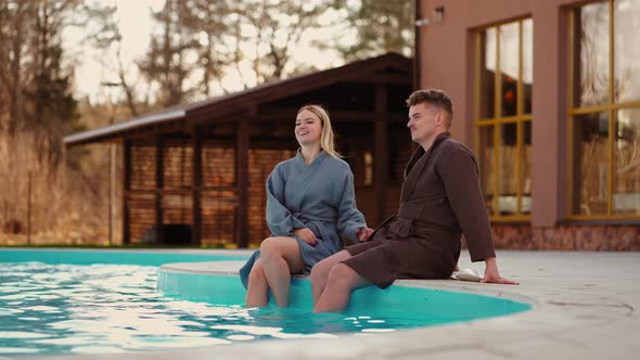 Honeymooners are Resting in Modern Spa Hotel with Outdoor Swimming Pool Young Man and Woman in Gowns alt