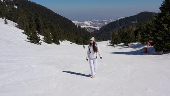 Young woman walking on ski track at the snowy mountain