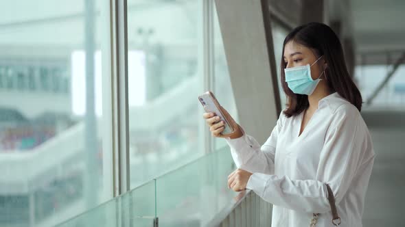 woman using smartphone and wearing medical mask for prevention from coronavirus (Covid-19) pandemic alt
