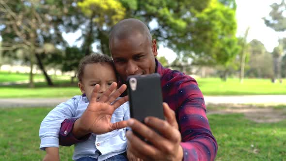 African American Father Waving and Making Selfie with Son alt